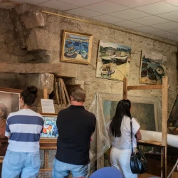 Dans une salle remplie de tableaux, des personnes en regardent dans différentes directions.