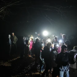 Des marcheurs à l'arrêt de nuit, ils sont équipés de lampes frontales qui permet de distinguer des personnes et des branches d'arbres.