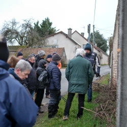 Groupe de personnes arrêtées dans un village, on voit des maisons en arrière plan, le temps est gris
